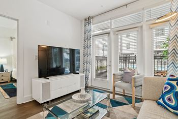 a living room with a couch and a glass coffee table and a television at Link Apartments® Mint Street, Charlotte, North Carolina